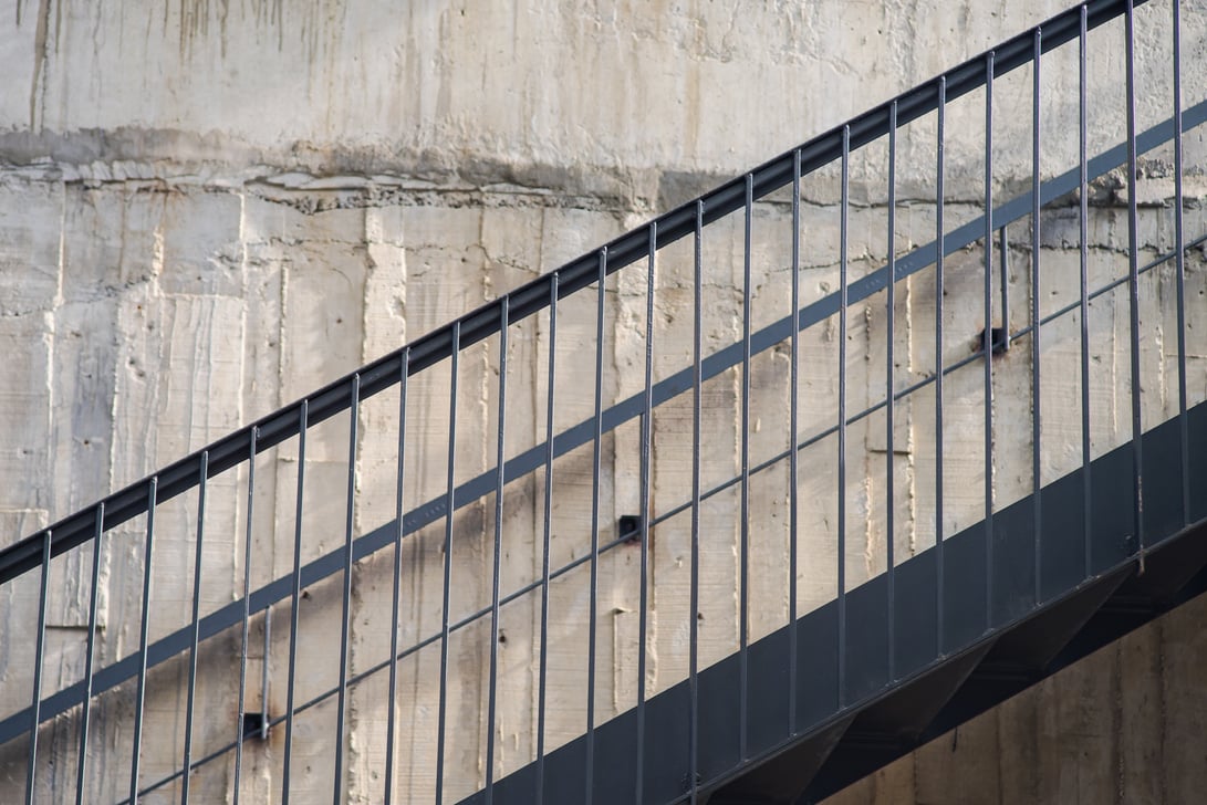 An iron ladder next to an old cement wall